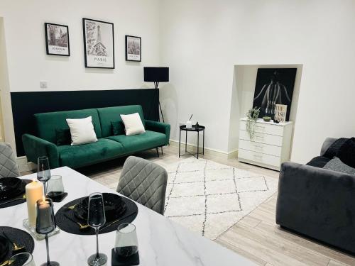 a living room with a green couch and a table at High-Spec Apartment in London - City Centre & Next To Tube in Ealing