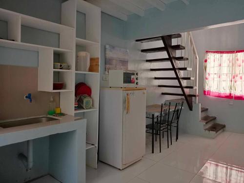 uma cozinha com um frigorífico e uma mesa com cadeiras em Merj's Guest House in Cavite em Trece Martires