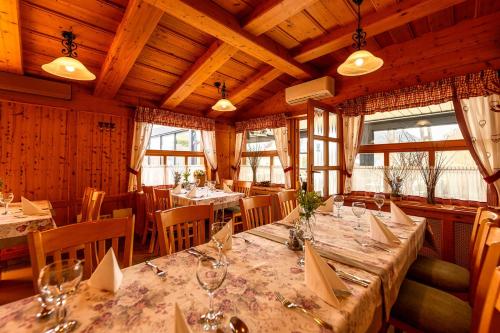 a dining room with tables and chairs and windows at Kakukk Vendéglő Panzió in Bánd