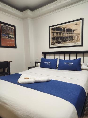 een slaapkamer met een groot bed met blauwe en witte kussens bij Hotel Manoa in Cúcuta