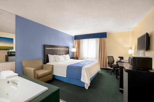 Habitación de hotel con cama, escritorio y TV. en The Cayuga Inn at the Finger Lakes en Auburn