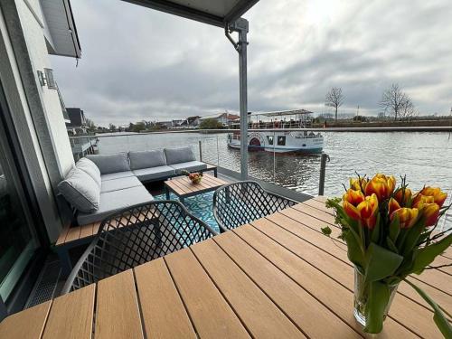 a balcony with a table and a boat on the water at Seeperle Meerleben in Carolinensiel