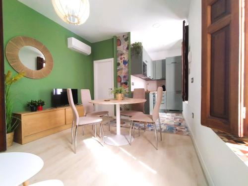 ein Esszimmer mit grünen Wänden sowie einem Tisch und Stühlen in der Unterkunft Casa Rístori Fábrica de Harinas in Manzanares