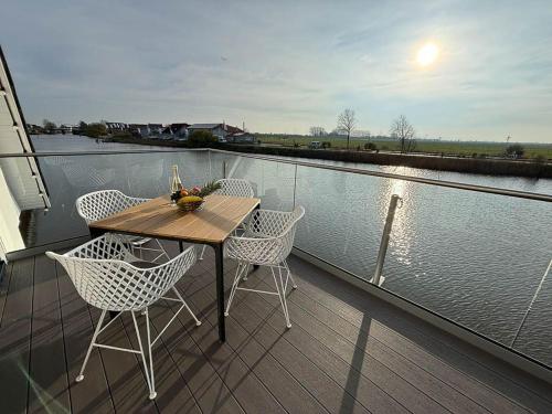 a table and chairs on a balcony next to the water at Seeperle Meerleben in Carolinensiel
