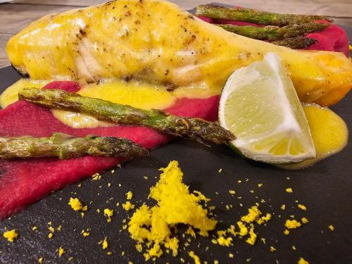 a close up of a plate of food with asparagus and lemon at Båtsfjord Royal Hotell in Båtsfjord
