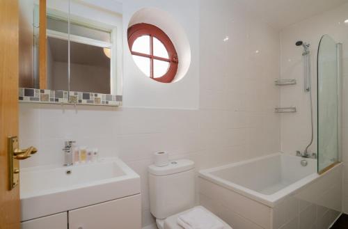 a bathroom with a toilet and a sink and a mirror at GuestReady - 4BR Home in Surrey Quays Canada Water in London
