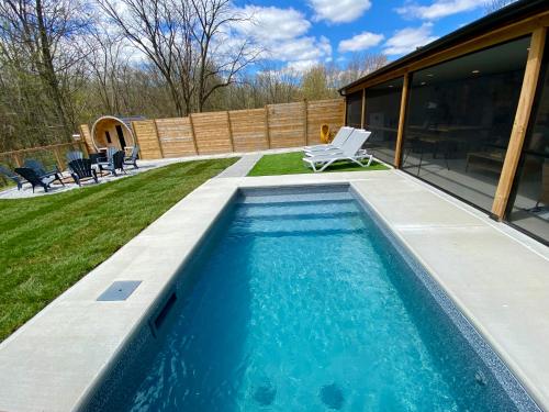 uma piscina com uma cadeira ao lado de uma casa em Kings Woods Lodge Resort in Wine Country with Heated Pool, Sauna & Games em Kingsville