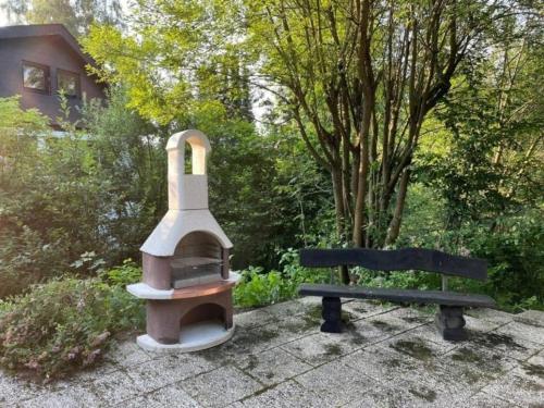 a wood fired oven and a bench in a garden at Chalet BERGgrün Willingen in Willingen