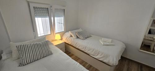 a small bedroom with two beds and a window at 2 bedrooms, Las Plumas in Torremolinos