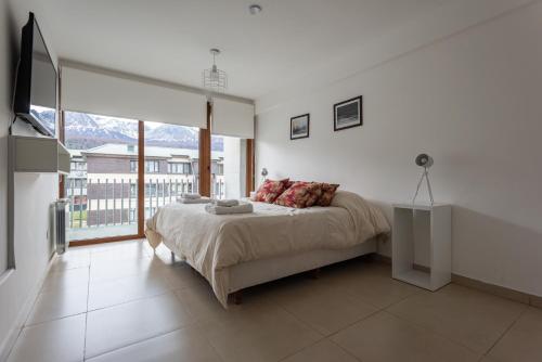 een slaapkamer met een bed en een groot raam bij Gente del Sur - Amundsen in Ushuaia
