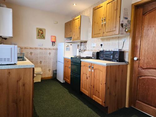 a kitchen with wooden cabinets and a black stove at Broughton Grove - Skipton, Pet Friendly, Canal Access in Skipton