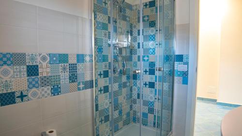 uma casa de banho com um chuveiro com azulejos azuis e brancos em Casa Del Nonno em Scario