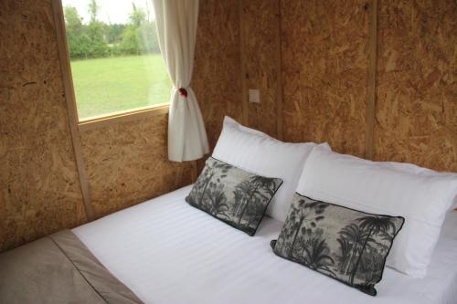 1 dormitorio con 1 cama con 2 almohadas y ventana en LOGIS DU GRAND PIN en Saint-Martin-des-Entrées