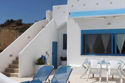 a white house with a blue door and chairs at Blue Sea Villa & Apartments in Makry Gialos