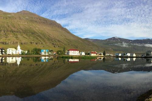 una piccola cittadina vicino a un bacino d'acqua con montagne di Árblik-Home away from home a Seyðisfjörður