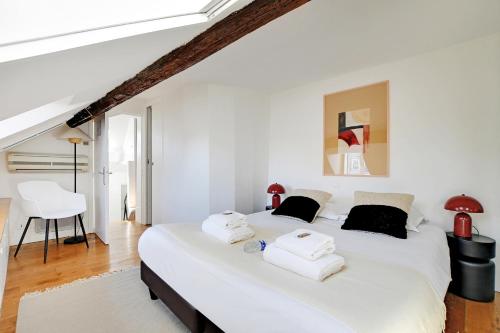 - une chambre avec un grand lit blanc et des serviettes dans l'établissement Residence central marais, à Paris