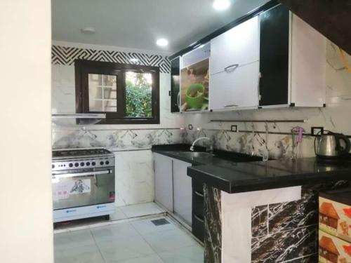 a kitchen with white appliances and black cabinets at امون الساحل الشمالي in Abû Zeira