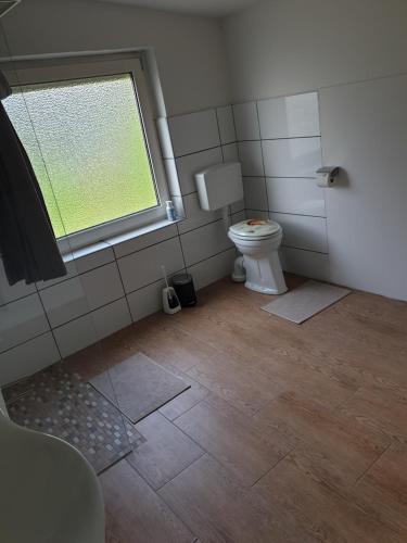 łazienka z toaletą i oknem w obiekcie Gasthaus Thiele w mieście Südbrookmerland