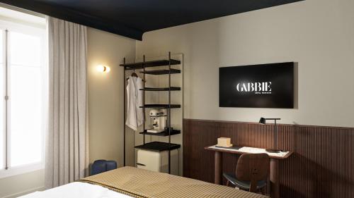 Hôtel Gabbie في باريس: غرفة نوم بسرير ومكتب وطاولة
