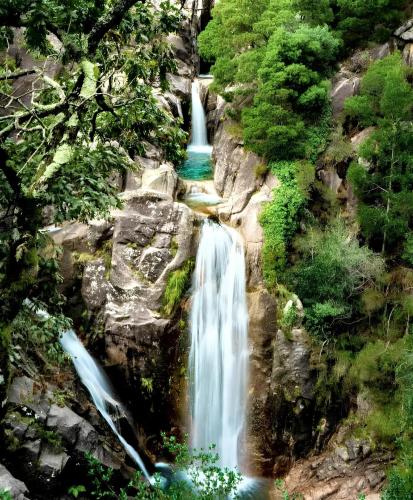 a waterfall in the middle of a forest at Charming house in Lindoso with terrace and parking included in Lindoso