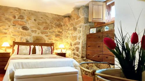 - une chambre avec un lit et un mur en pierre dans l'établissement 2 bedrooms house with furnished terrace and wifi at Lindoso, 