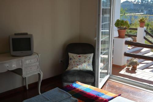 ein Wohnzimmer mit einem Stuhl und einem TV in der Unterkunft Casa do Tié in Quinta do Anjo