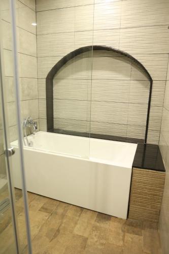 a white bath tub with a mirror in a bathroom at Mayilveedu Guest House in Tuticorin