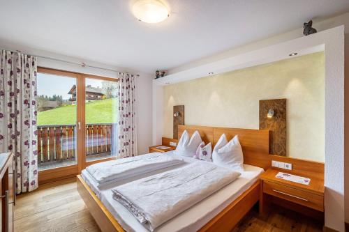 - une chambre avec un grand lit et une grande fenêtre dans l'établissement Stoffnerhof Apt Sonnenblume, à Monguelfo-Tesido