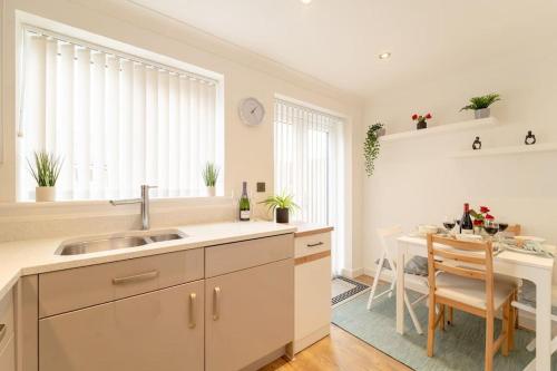 a kitchen with a sink and a dining room table at Stylish 3 Bed, 3 Bath, Garden & Drive for 2 cars in Colne
