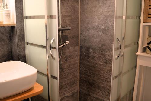 a bathroom with a glass shower door next to a toilet at Petite vague - maison atypique avec terrasse in Saint-Aubin-sur-Mer
