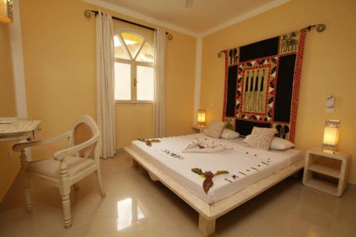 a bedroom with a bed and a chair and a window at Mwembe Resort - The Village in Malindi