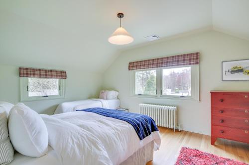 a bedroom with a bed and a dresser and two windows at Charming Greenwich Escape Near Wooded Trails! in Cos Cob