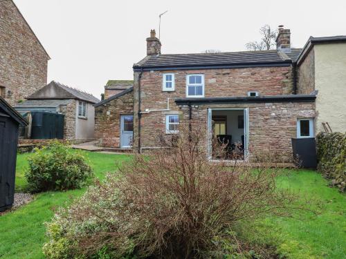 a brick house with its door open in a yard at Lime Tree Cottage in Kirkby Stephen