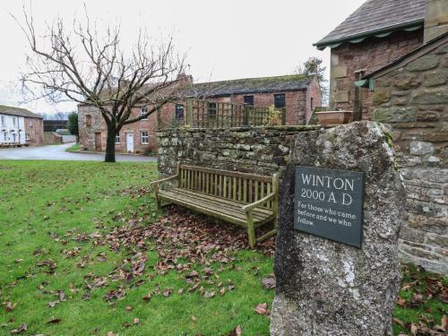 a sign on a stone wall next to a bench at Lime Tree Cottage in Kirkby Stephen