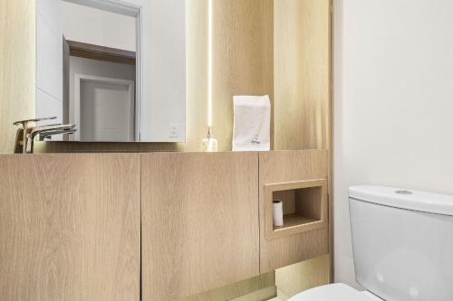 La salle de bains est pourvue de toilettes, d'un lavabo et d'un miroir. dans l'établissement Apartamento Essence 2 Suítes by Achei Gramado, à Gramado