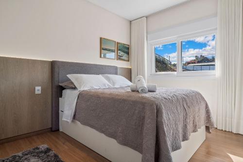 1 dormitorio con cama y ventana en Apartamento Essence 2 Suítes by Achei Gramado, en Gramado