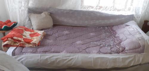 a bed with a purple comforter on top of it at guest house in buhal in Përmet