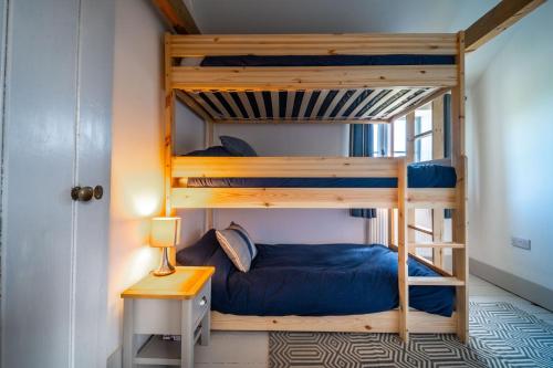 a bedroom with two bunk beds and a table at Ruthie Cottage by Big Skies Cottages in Bacton