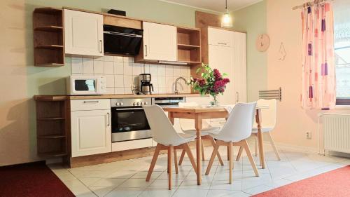 Una cocina con una mesa de madera y sillas blancas. en Ferienhof Sommergarten, en Markische Heide