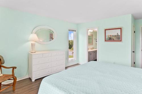 a white bedroom with a bed and a mirror at Nautical Watch on Harbor Island in Oceanmarsh Subdivision