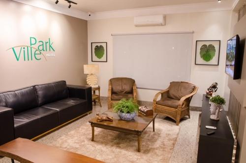 a living room with a black leather couch and chairs at Ville Park Hotel in Ourinhos