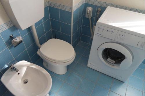 a bathroom with a toilet and a washing machine at Settimo cielo in Rosolina Mare