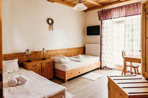 a bedroom with two beds and a desk and a window at Kakukk Vendéglő Panzió in Bánd