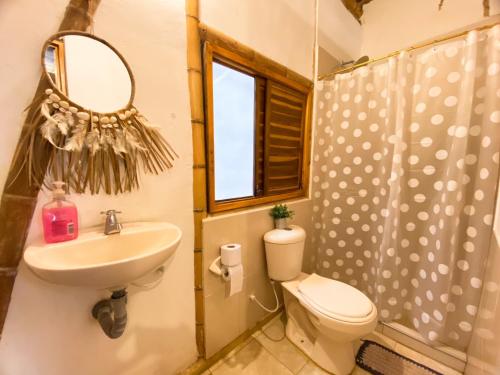 een badkamer met een wastafel, een toilet en een spiegel bij Rincon del Mar Palomino in Palomino
