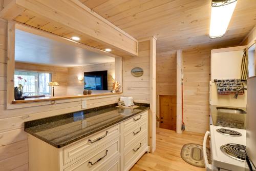 a log cabin kitchen with white cabinets and a stove at Lake George Vacation Rental - Walk to the Water! in Lake George