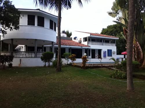 a white house with palm trees in front of it at Marina Beach Front homes in Mombasa