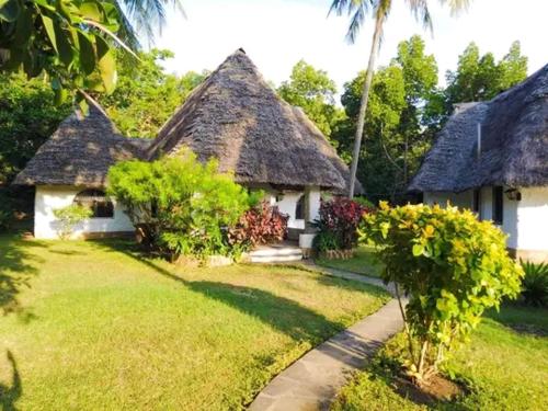a house with a thatched roof and a grass yard at Marina Beach Front homes in Mombasa