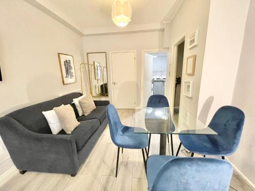 a living room with a glass table and blue chairs at Stylish studio on Edgware Road (Marylebone) in London