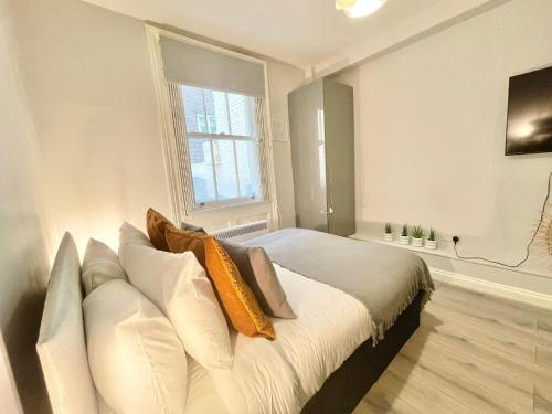 una camera da letto con letto, cuscini e finestra di Stylish studio on Edgware Road (Marylebone) a Londra