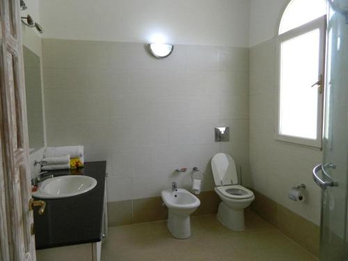 a bathroom with a sink and a toilet and a window at Mwembe Resort - The Village in Malindi